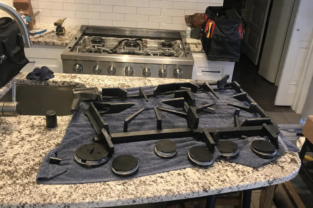 Grates and burner caps off the appliance and drying on a towel before they are refitted, rangetop visible behind