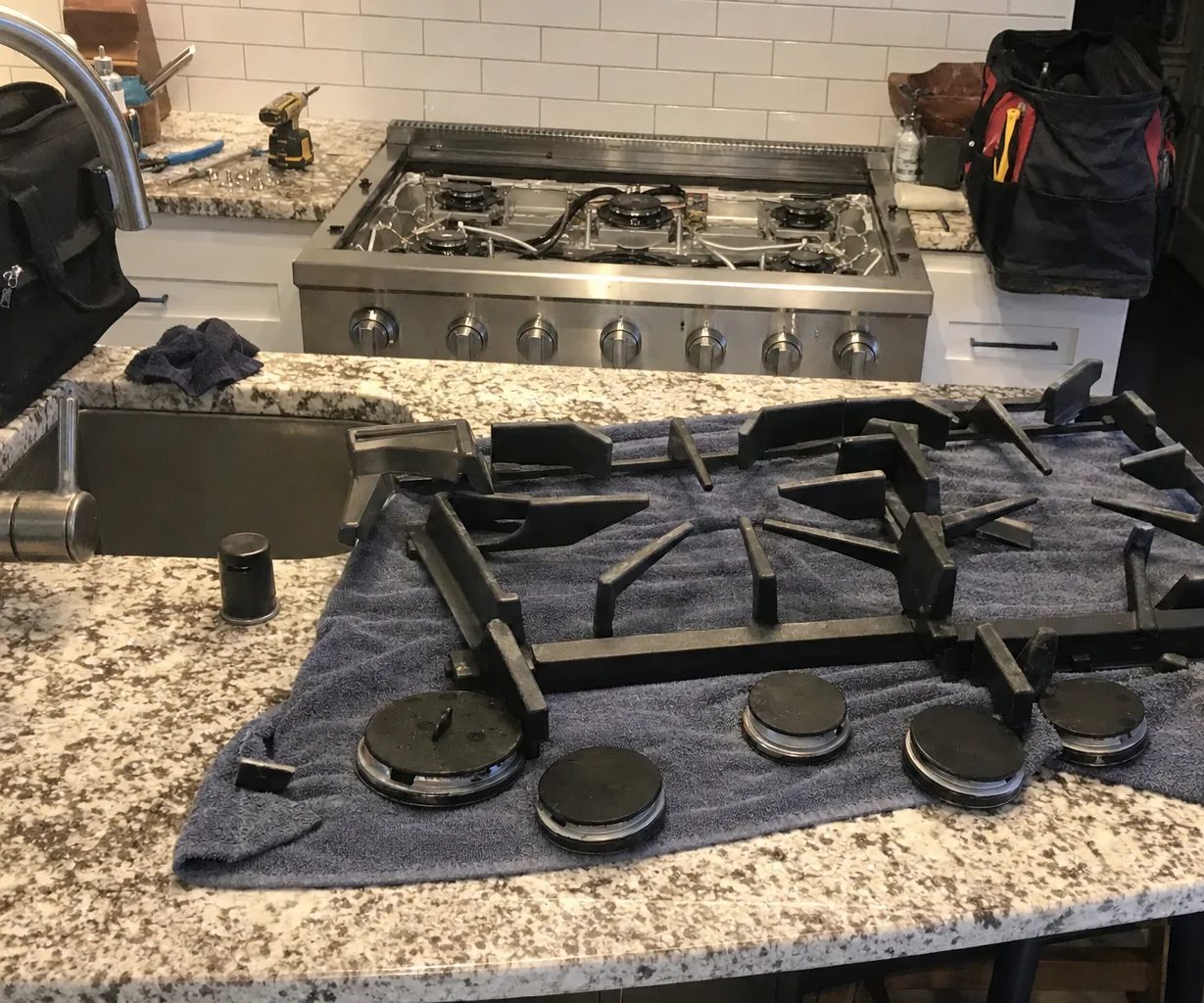 A six-burner rangetop with its grates and burner caps removed, sitting in the cabinet run it was fitted into